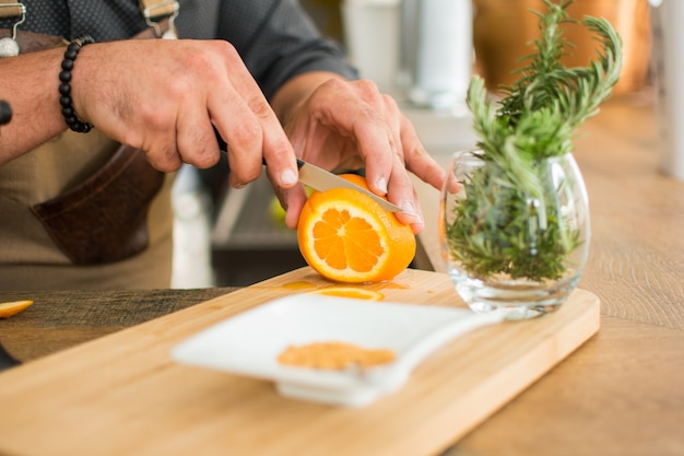 Cameriere che prepara un cocktail che taglia arancia