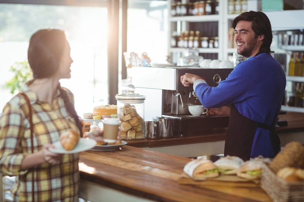 Cameriere che produce tazza di caffè mentre interagendo con il cliente