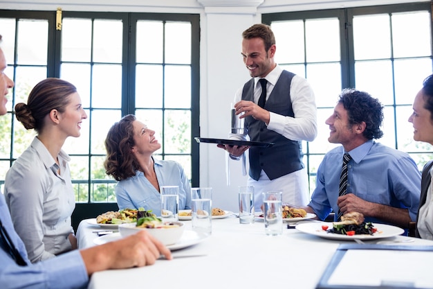 Cameriere che serve acqua agli uomini d'affari