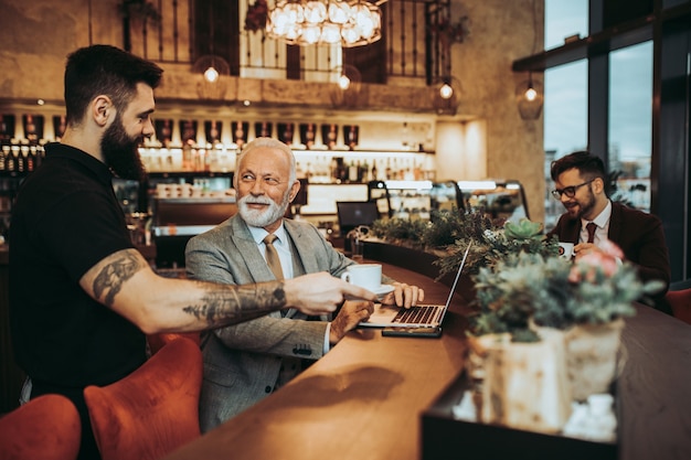 Cameriere che serve caffè agli uomini d'affari nel ristorante.