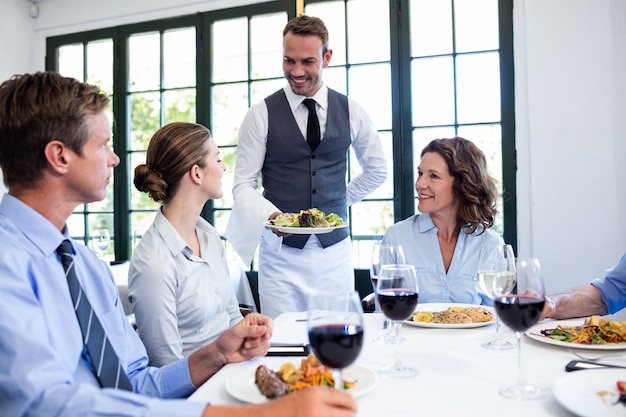 Cameriere che serve insalata per uomini d'affari