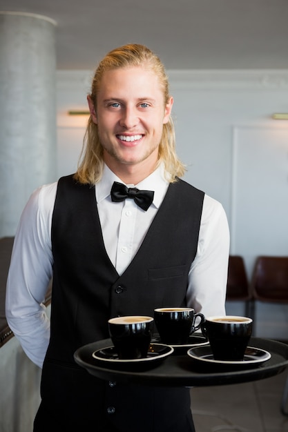 Cameriere che tiene un vassoio con le tazze di caffè in ristorante