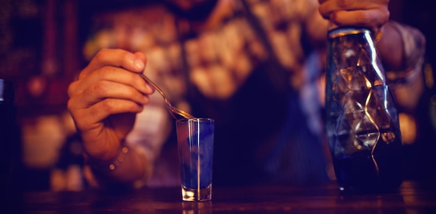 Cameriere che versa cocktail in bicchierini al bancone