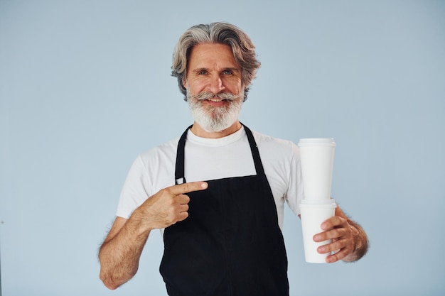 Cameriere con bevande in mano Uomo moderno ed elegante con capelli grigi e barba all'interno