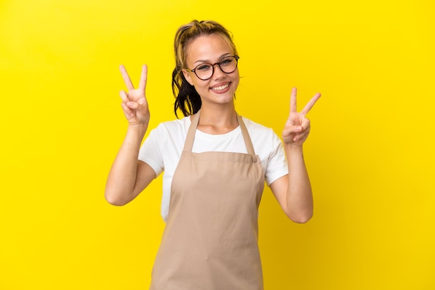 Cameriere del ristorante Ragazza russa isolata su sfondo giallo che mostra il segno della vittoria con entrambe le mani