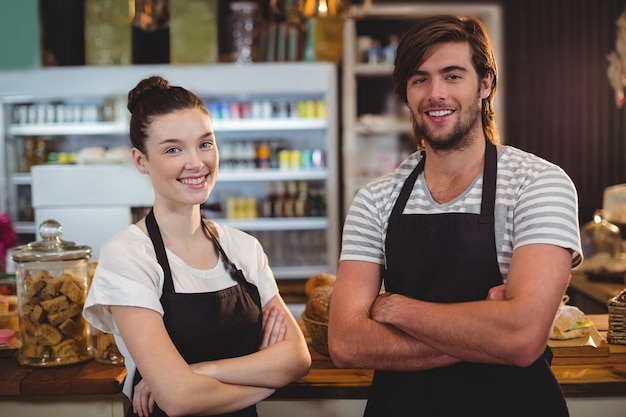 Cameriere e cameriera in piedi con le braccia incrociate nella caffetteria