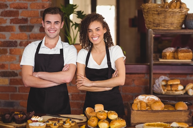 Cameriere e cameriera sorridenti con le braccia attraversate