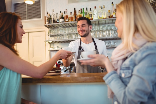 Cameriere felice che serve caffè al cliente presso la caffetteria