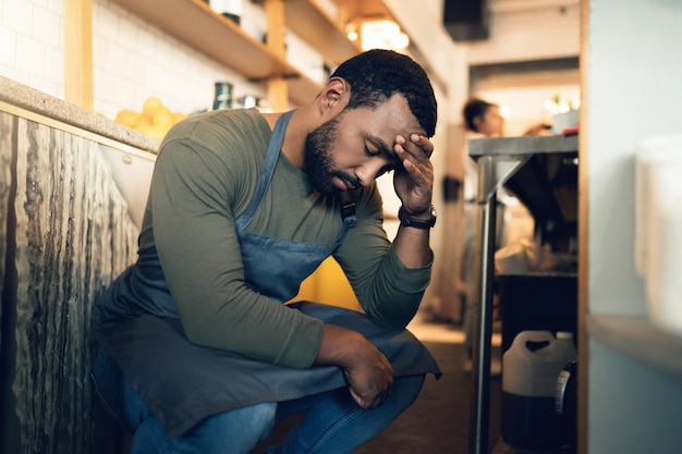 Cameriere in una caffetteria e stanco per lo stress mal di testa o rimpianto per un errore fallito o stanchezza al lavoro Barista persona burnout e mal di testa con ansia salute mentale o depressione in ristorante