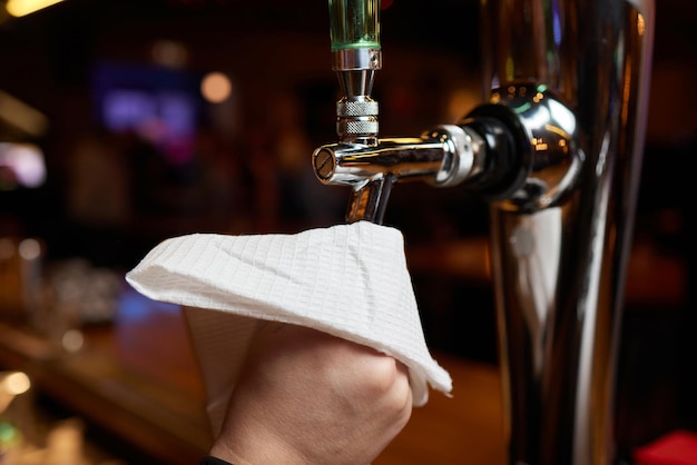 Cameriere o barista che puliscono i rubinetti della birra sul bancone del pub e del ristorante