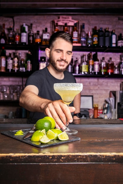 Cameriere sorridente che lascia un cocktail sopra il bancone del bar