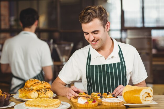 Cameriere sorridente che riordina i pasticcini