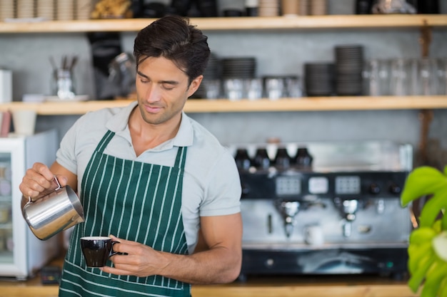 Cameriere sorridente che versa una tazza di caffè