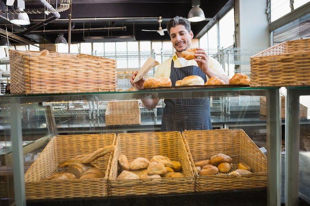 Cameriere sorridente in grembiule che sceglie pane