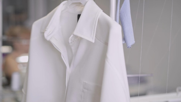 Camicia bianca sull'appendiabiti in studio atelier sfondo sfocato