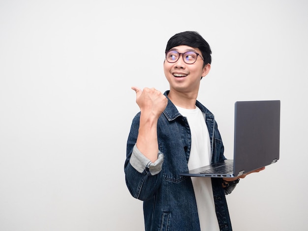 Camicia di jeans da giovane uomo con gli occhiali con il dito puntato sul laptop nello spazio della copia