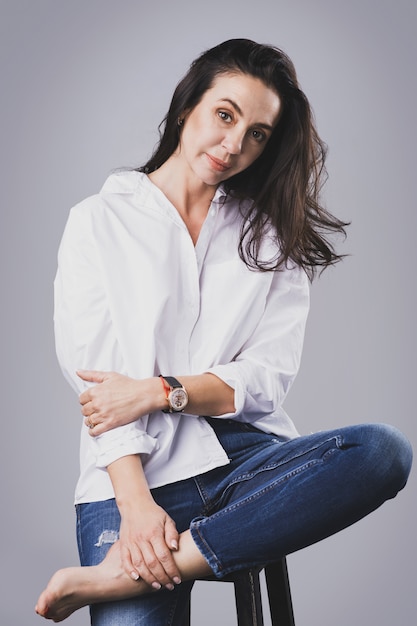 Camicia e jeans bianchi d'uso della bella donna invecchiata mezzo