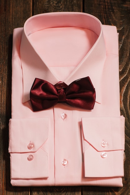 Camicia maschio rosa con papillon in raso sulla scrivania in legno