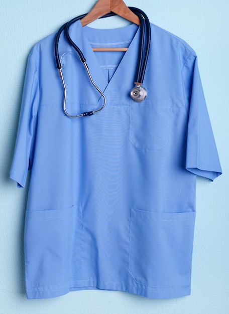 Camicia medico con stetoscopio su appendiabiti su sfondo blu