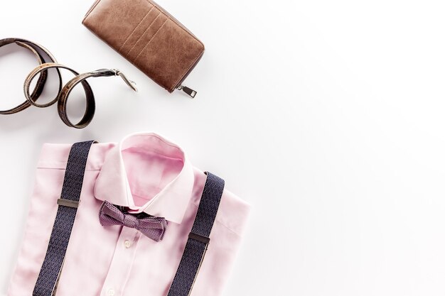 Camicia rosa e accessori sul tavolo bianco