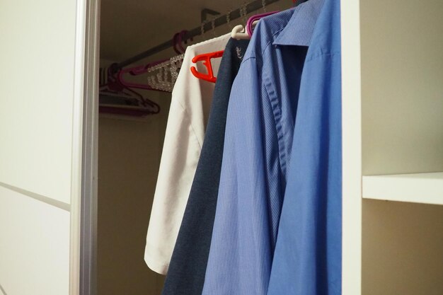Camicie da uomo appese alle grucce in un armadio bianco aperto organizzazione della moda maschile delle cose in un armadio