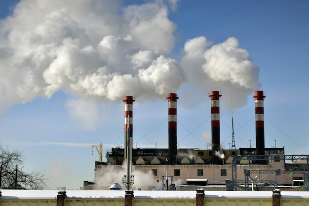 Camini della centrale elettrica sopra il fondo del cielo blu