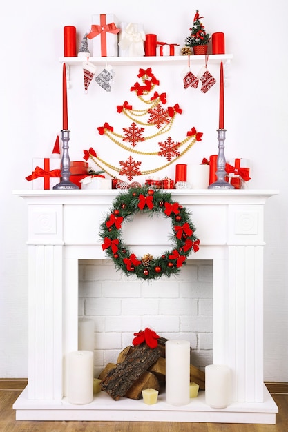 Camino con decorazioni natalizie su pavimento in legno e sfondo muro bianco