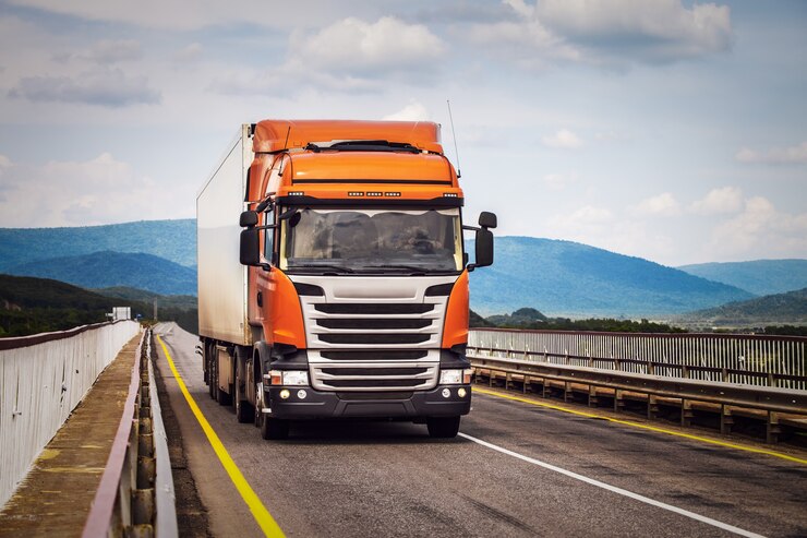 Camion arancione su una strada che si muove da un ponte