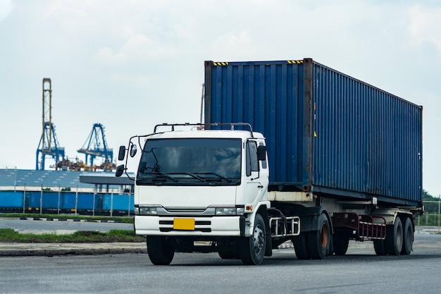 Camion blu del contenitore di carico nella logistica del porto della nave. Industria dei trasporti nel concetto di affari del porto.
