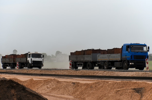 Camion che trasportano merci lungo una strada in costruzione.
