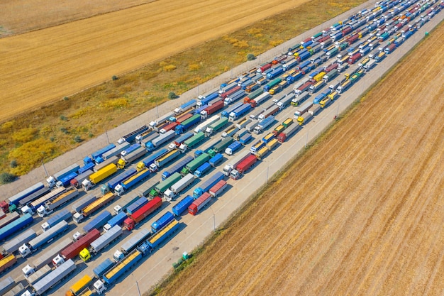 Camion multicolori vicino al terminal portuale aspettano di essere caricati o scaricati. Centro logistico moderno. Vista aerea.