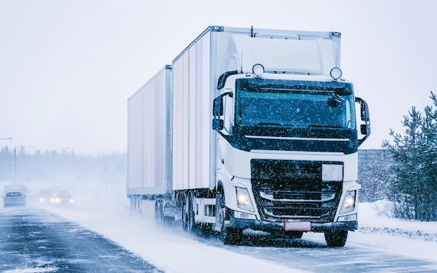 Camion nella strada invernale della neve della Finlandia. Camionista in autostrada. Camion che fa lavori di logistica. Semirimorchio con conducente. Grande auto da carico. Consegna merci. Industria dell'esportazione dei trasporti. Contenitore con merci