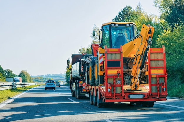 Camion rimorchio bisarca con dumper che trasporta trattore agricolo su strada, in Slovenia.