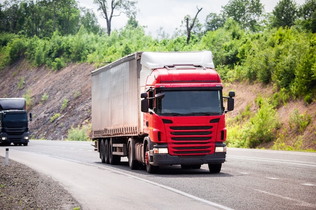 Camion rossi e neri che si muovono lungo una strada