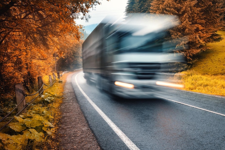 Foto camion sfocato sulla strada in autunno foresta nebbiosa in una giornata piovosa bella carreggiata di montagna alberi fogliame arancione nella nebbia paesaggio con auto in movimento strada attraverso boschi in autunno viaggio viaggio su strada
