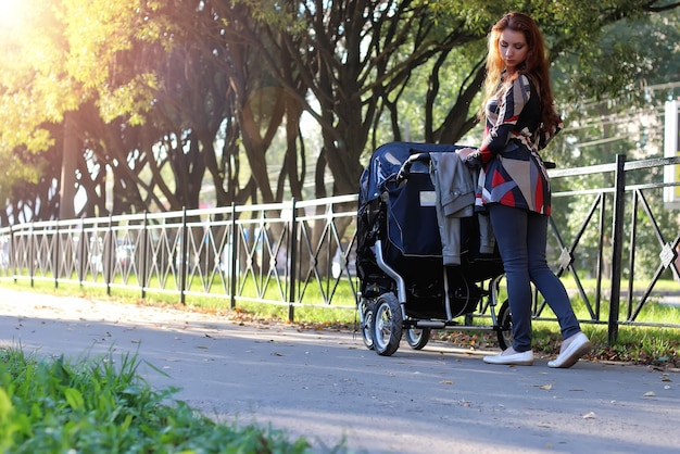 Cammina le donne con la luce del sole estivo del passeggino