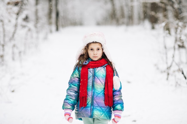 Cammina nella foresta invernale. La ragazza felice gioca con una neve nel giorno di inverno.