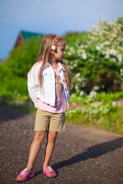 Camminata sveglia della bambina all'aperto, divertendosi e ridendo