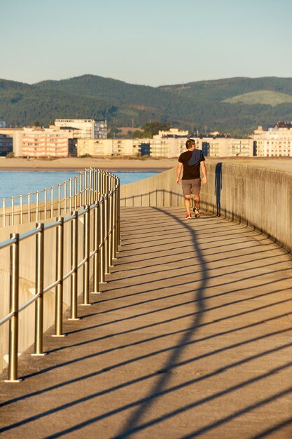 Camminatore solitario all'alba sulla passerella di cemento