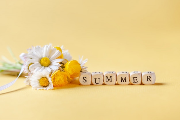 Camomila del fiore del mazzo con estate del testo su fondo giallo.