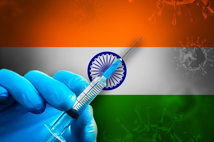 Campagna di vaccinazione dell'India Covid19 La mano in un guanto di gomma blu tiene la siringa davanti alla bandiera
