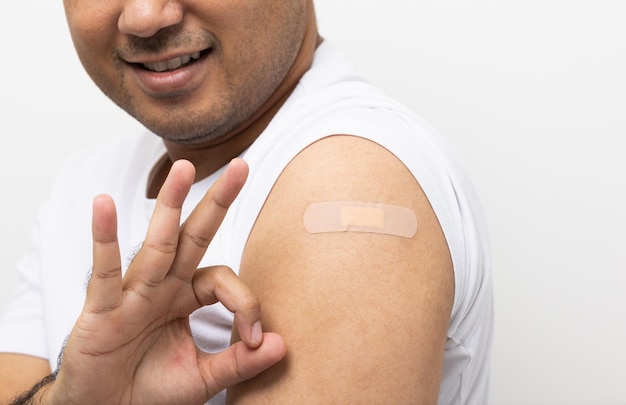 Campagna di vaccinazioneClose up Giovane indiano che riceve il vaccino contro il coronavirus immune e mostra il braccio con cerotto bendato su sfondo bianco isolato
