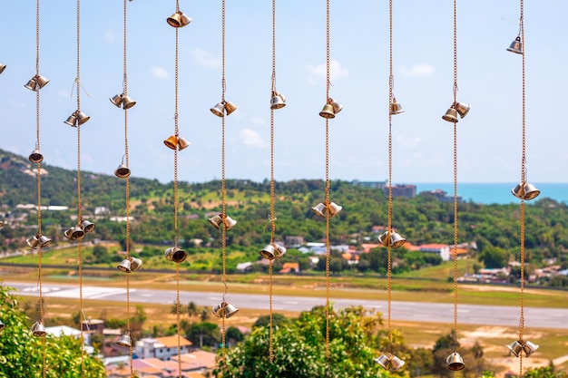 Campane di elementi decorativi su una catena metallica sullo sfondo di un paesaggio tropicale