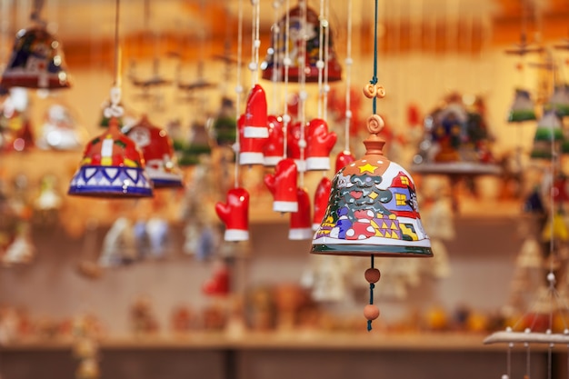 Campane in ceramica colorate vendute sul mercatino di Natale in Europa. Regalo di souvenir in argilla campana in fiera.