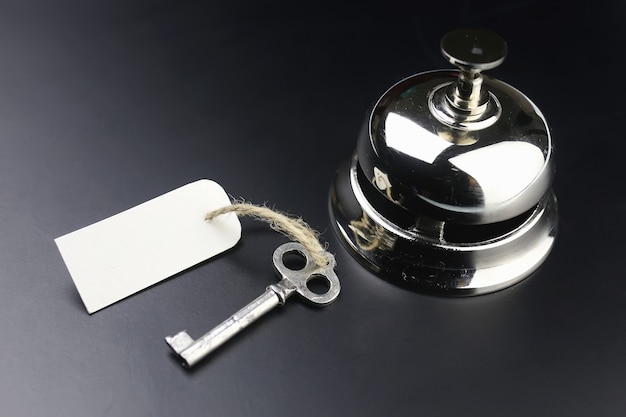 Campanello d'argento e chiave alla reception dell'hotel su sfondo nero