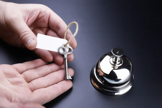 Campanello d'argento e chiave alla reception dell'hotel su sfondo nero