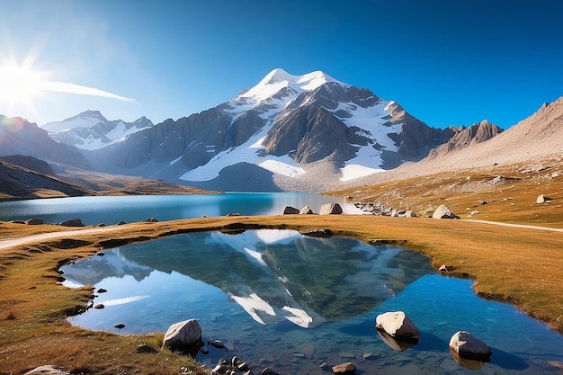 Campeggio con tenda vicino a un lago ad alta quota sulle Alpi riflesso della catena montuosa innevata e panoramico