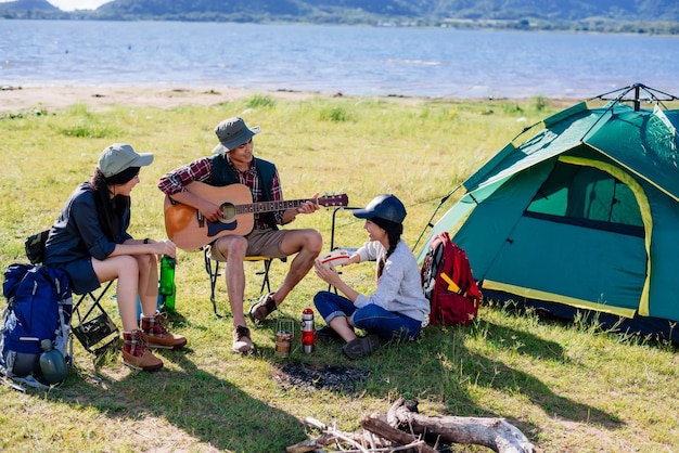 Campeggio in natura amici felici festeggiano e suonano la chitarra insieme in estate nella foresta naturale