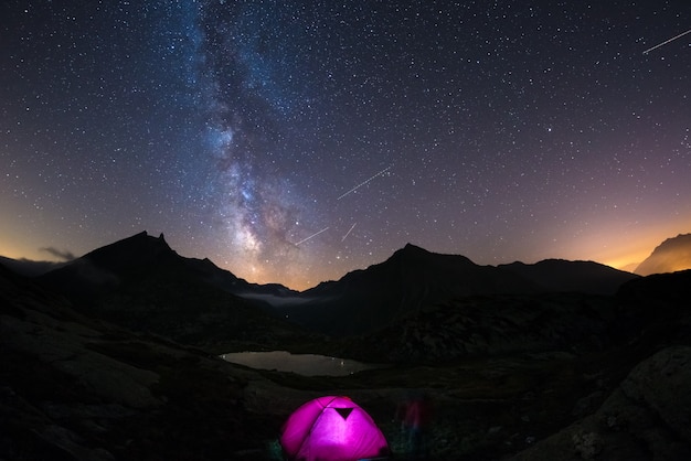 Campeggio sotto il cielo stellato e la Via Lattea in alta quota sulle Alpi.