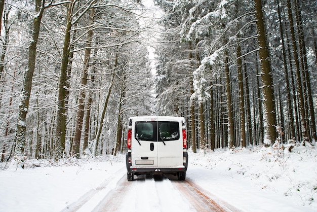 Camper che guida su una strada attraverso una foresta innevata in vacanza avventura invernale